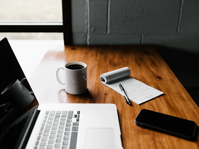Escritorio con un portátil, un cuaderno y una taza de café