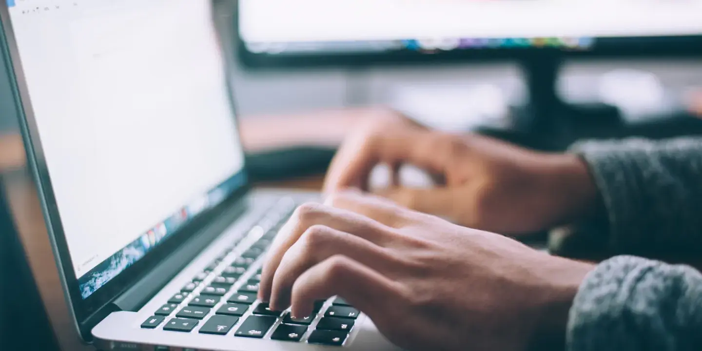 Manos escribiendo en el teclado de un portátil durante el desarrollo de una web